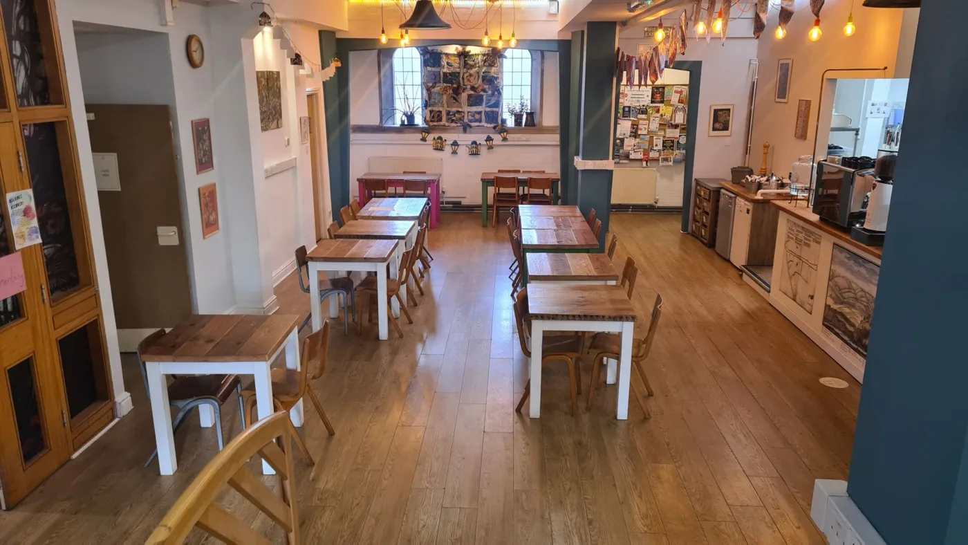 The café at St Sidwell's Community Centre: wooden tables and chairs down a long room with a counter on the right